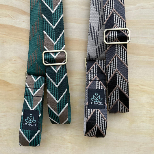 Two patterned belts with buckles on a wooden surface, featuring the Lovel brand.