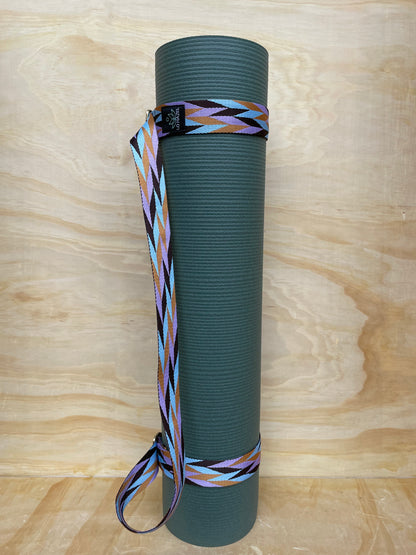 Green yoga mat with a colorful strap on a wooden surface