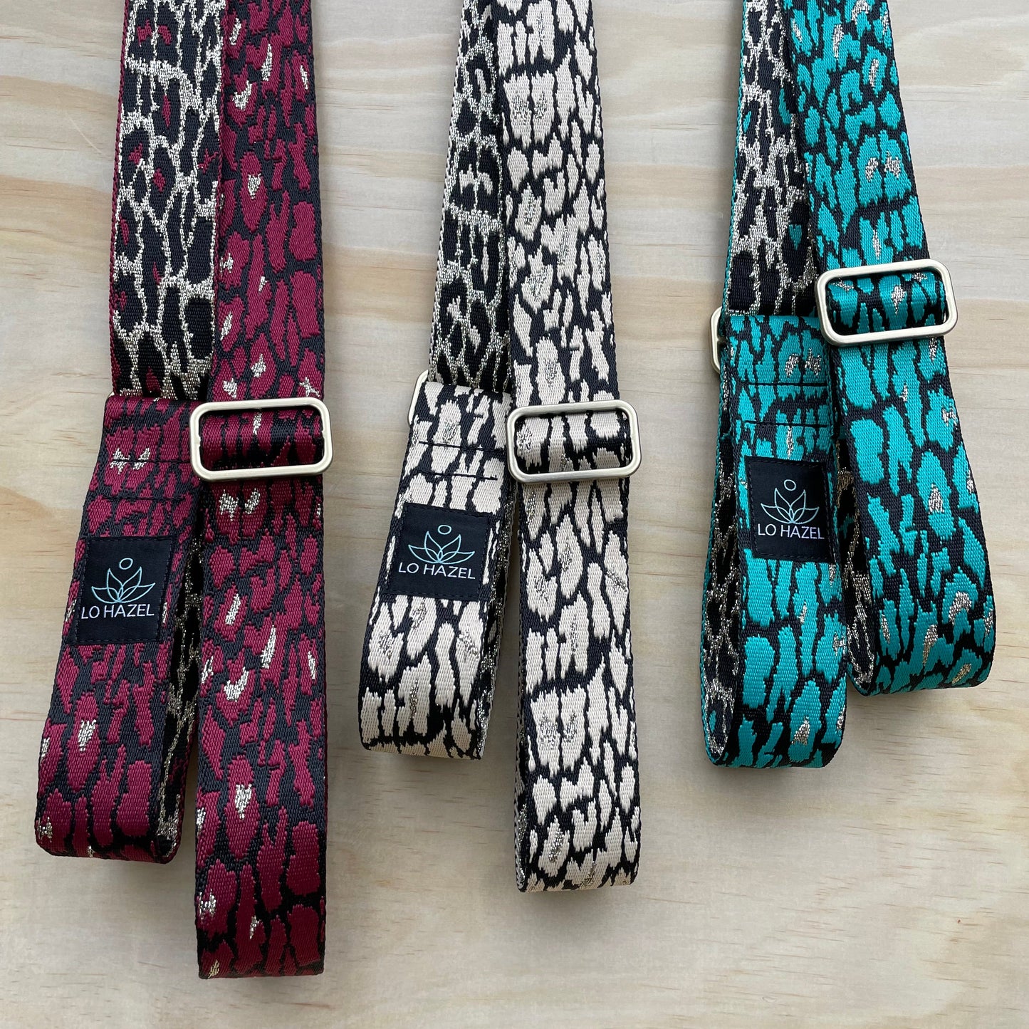 Three patterned straps in purple, white, and blue on a wooden surface