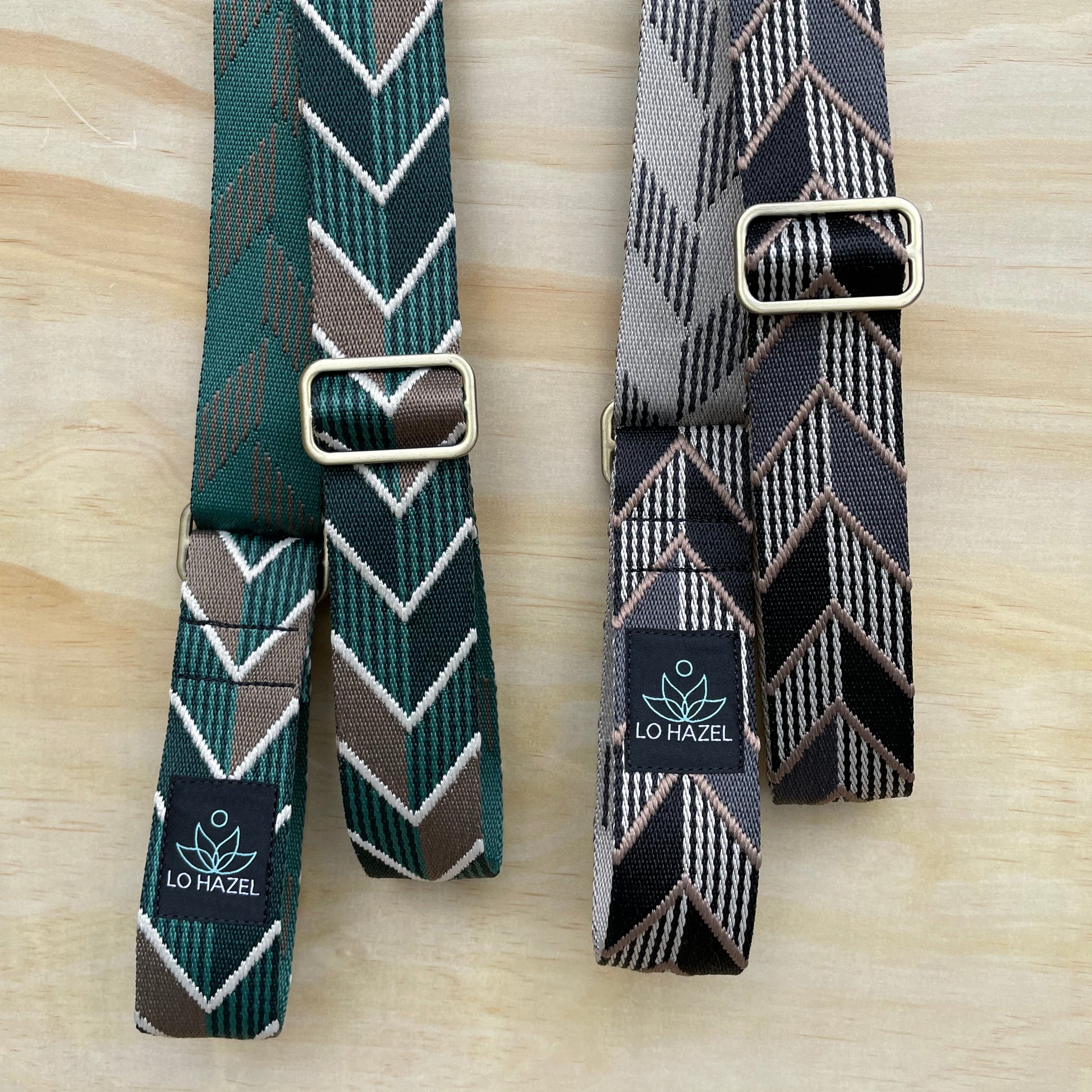 Two patterned belts with buckles on a wooden surface, featuring the Lovel brand.