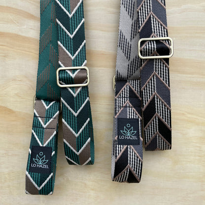 Two patterned belts with buckles on a wooden surface, featuring the Lovel brand.